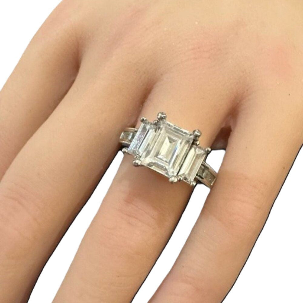 Silver ring with a large diamond on a finger against a white background