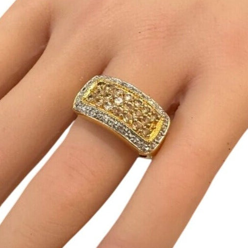 Gold ring with gemstones on a finger against a white background