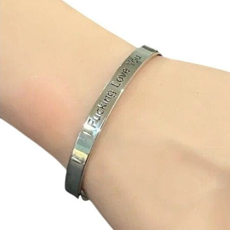 Silver bracelet with engraved text on a wrist against a white background