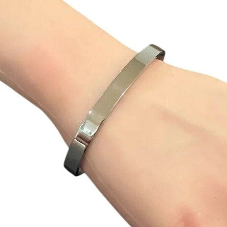 Silver bracelet on a wrist with a plain background
