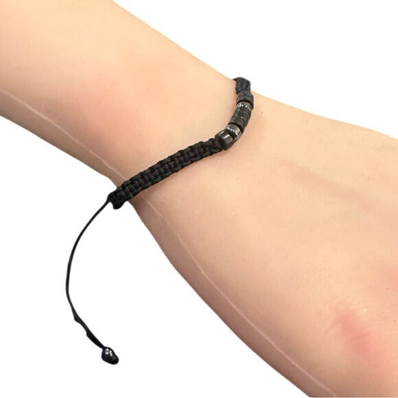 Black braided bracelet on a wrist against a white background