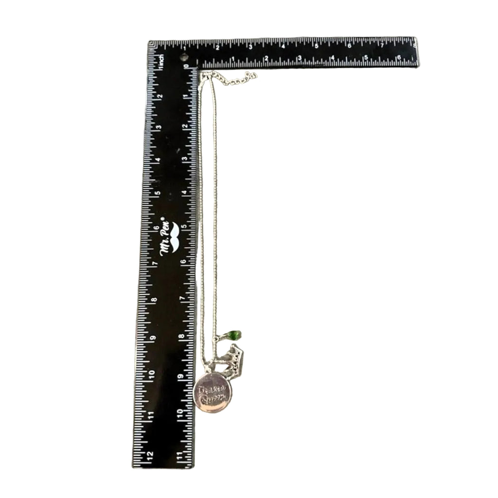 Necklace with charms on a ruler for scale on a textured surface