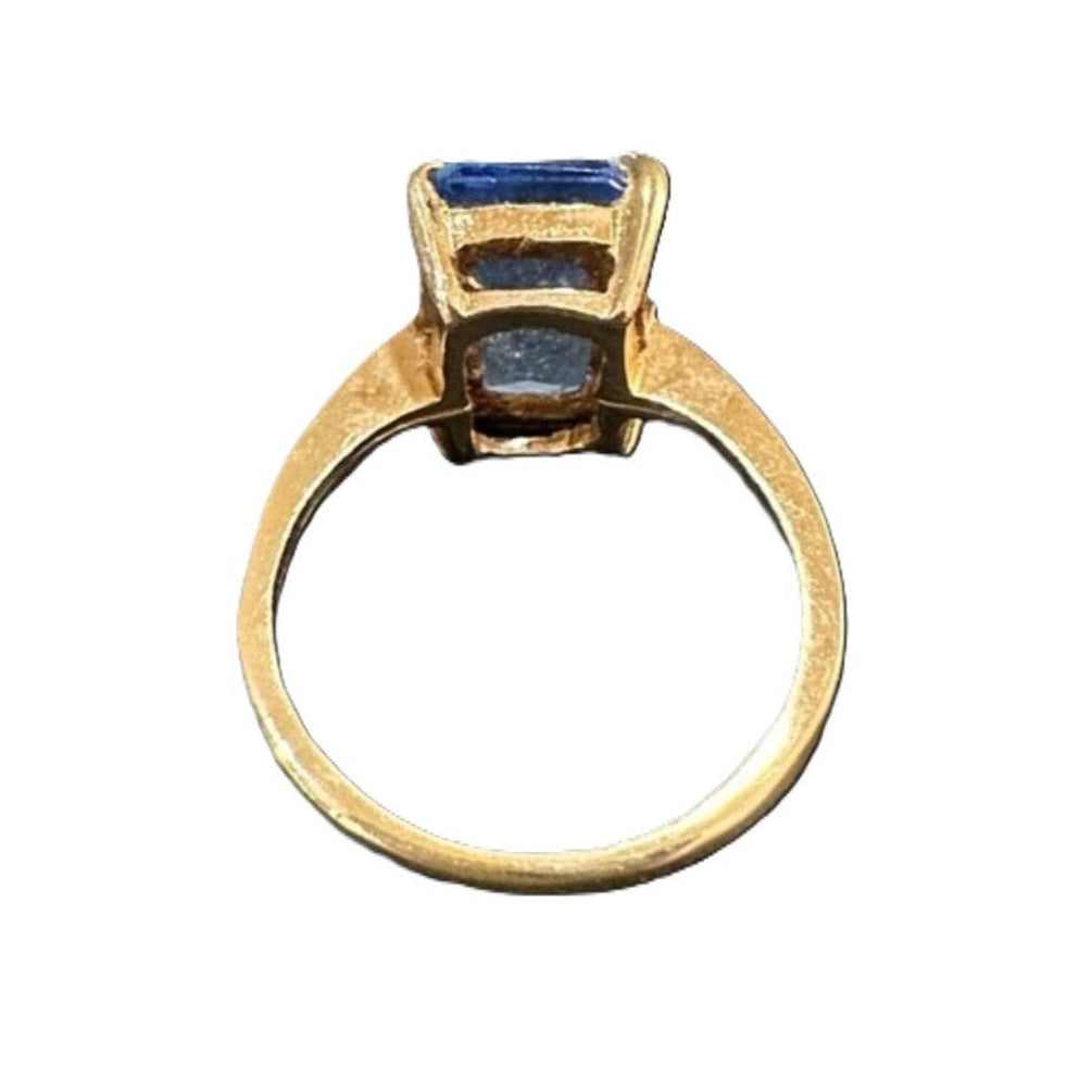 Gold ring with a blue gemstone on a white background