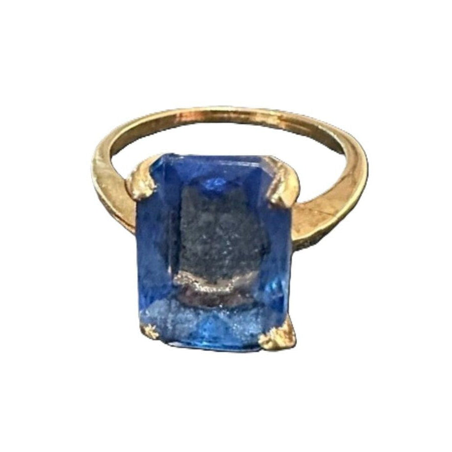 Gold ring with a large blue gemstone on a white background