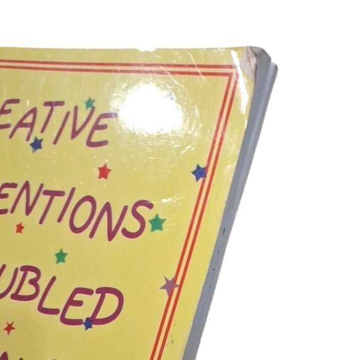 Close-up of a yellow notebook with text and star designs on a white background