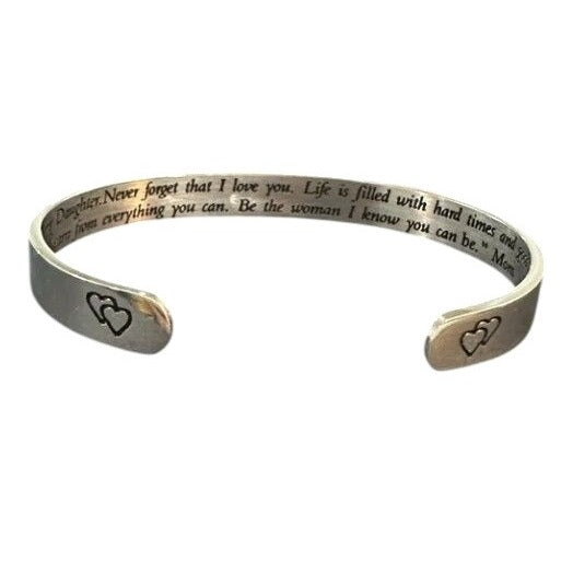 Silver bracelet with engraved text and heart designs on a white background