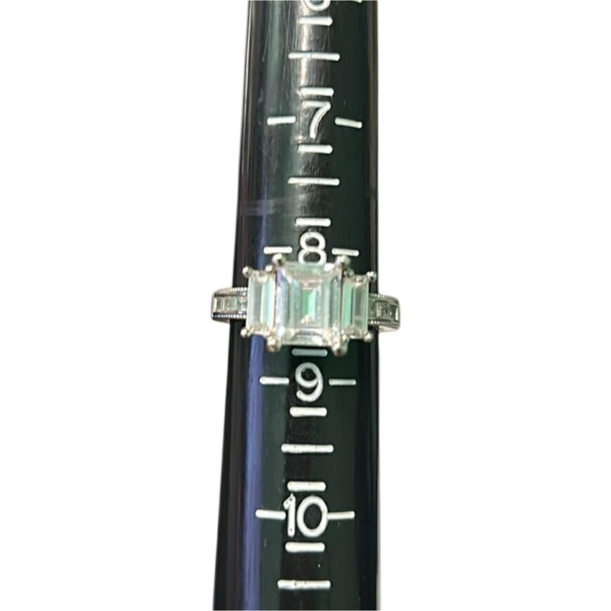 Ring with emerald-cut gemstone on a black background with measurement scale