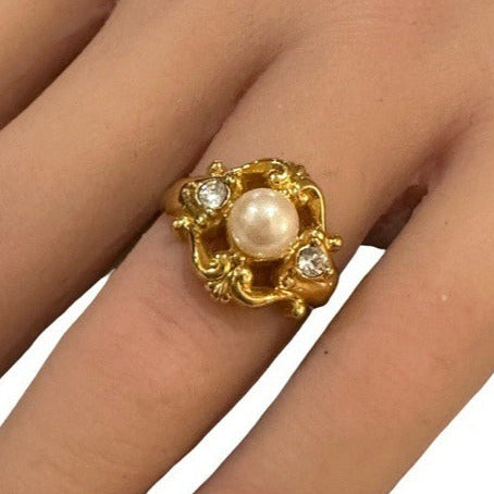 Gold ring with a pearl on a hand against a white background