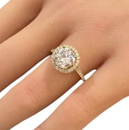 Gold ring with a large diamond on a hand against a white background