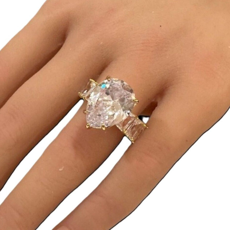 Gold ring with a large gemstone on a hand against a white background