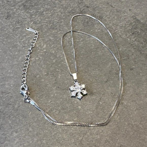 Silver necklace with a snowflake pendant on a gray surface