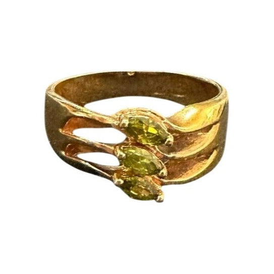 Gold ring with green gemstones on a white background