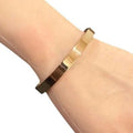 Gold bracelet on a wrist with a plain background