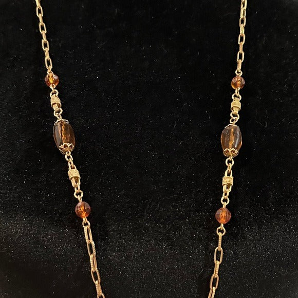 Necklace with gold chain and brown beads on a black background