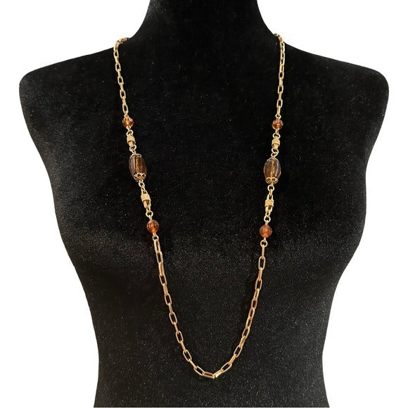 Gold chain necklace with amber beads on a black mannequin bust.