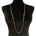 Gold chain necklace with amber beads on a black mannequin bust.