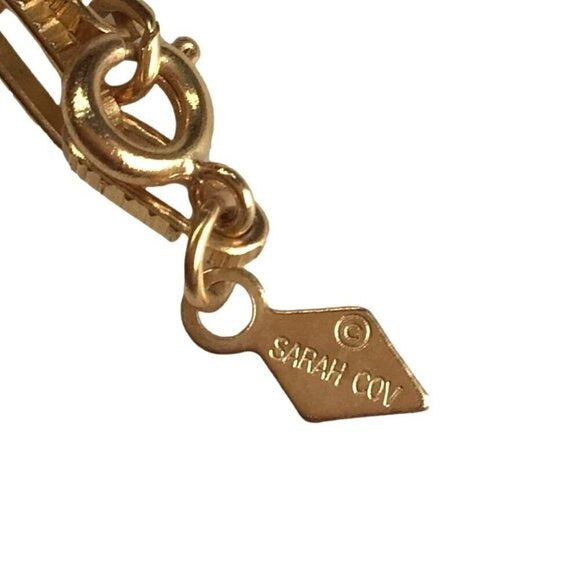 Gold bracelet with a 'Sarah Cov' tag on a white background