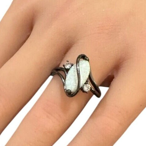 Silver ring with a white stone on a hand against a white background