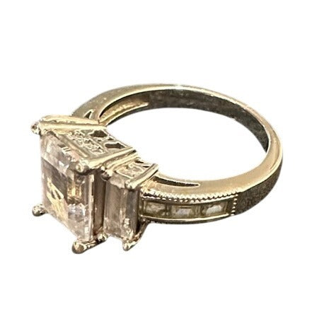 Silver ring with a large diamond and smaller diamonds on the band against a white background
