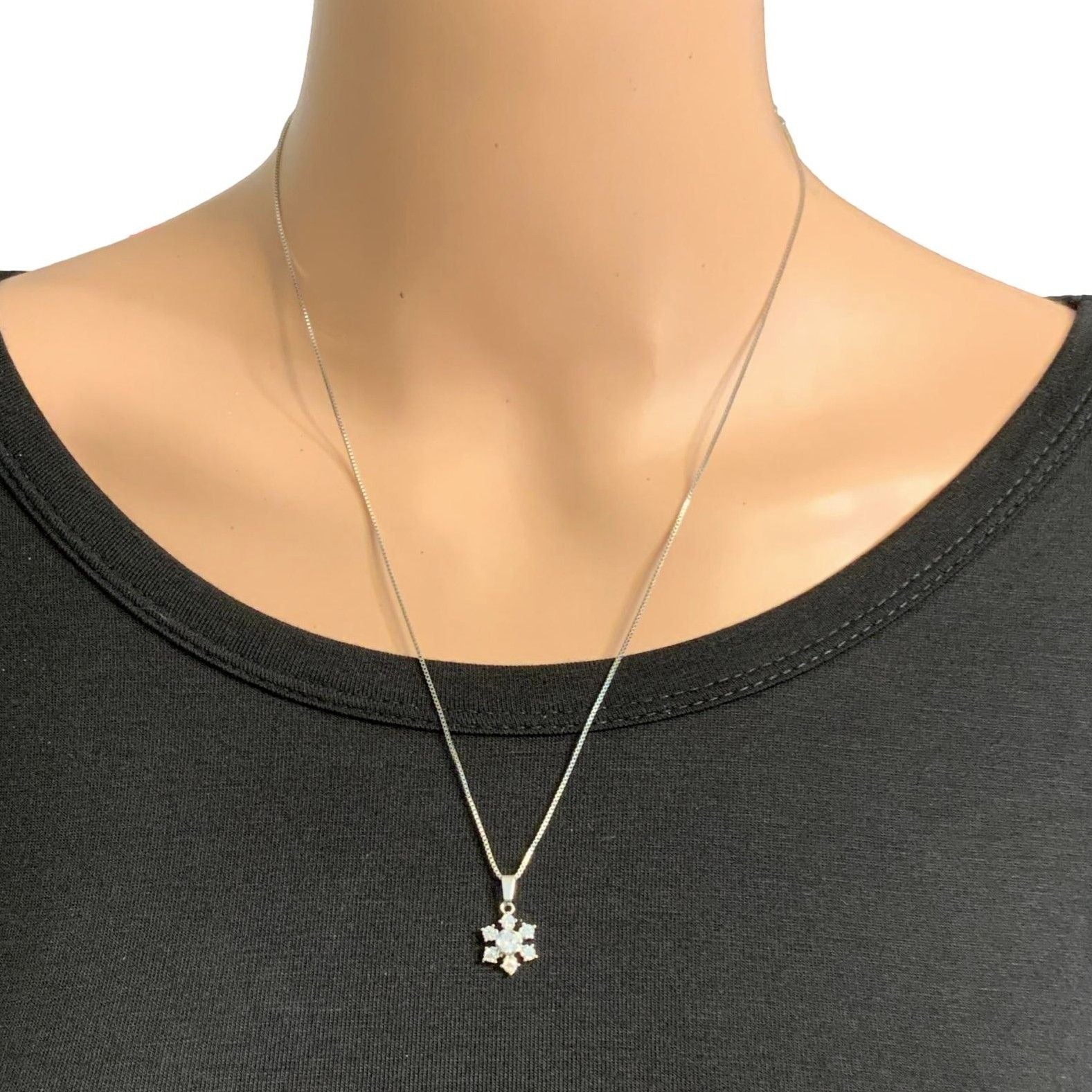Mannequin wearing a black top with a silver necklace featuring a star-shaped pendant.