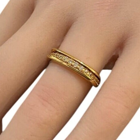 Gold ring with small diamonds on a finger against a white background