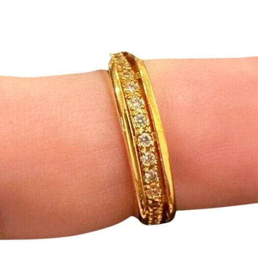 Gold bracelet with embedded stones on a wrist against a white background
