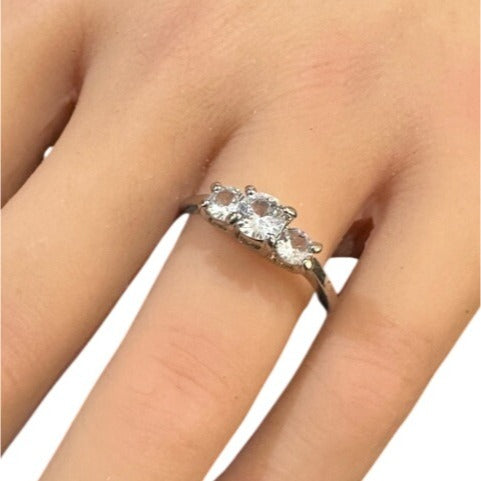 Silver ring with three diamonds on a finger against a white background
