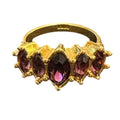 Gold ring with purple gemstones on a white background