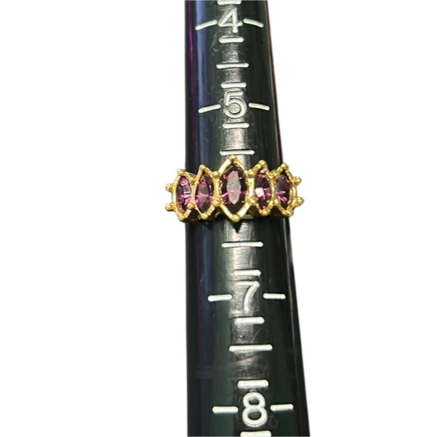 Gold ring with purple gemstones on a black measuring stick