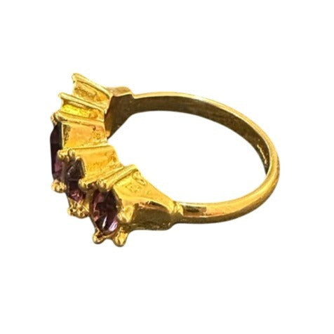 Gold ring with purple gemstones on a white background